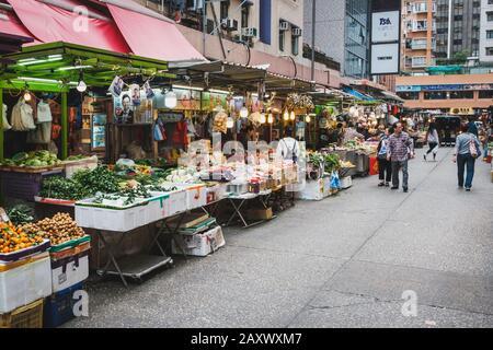 Hong Kong - November, 2019: People selling fruits and vegetables on  street food market in Hong kong Stock Photo