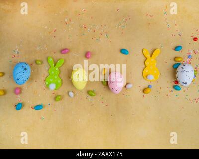 Toy cute bunny and colorful easter eggs, delicious candies on yellow background. bunny. Funny decoration. Happy Easter concept Stock Photo