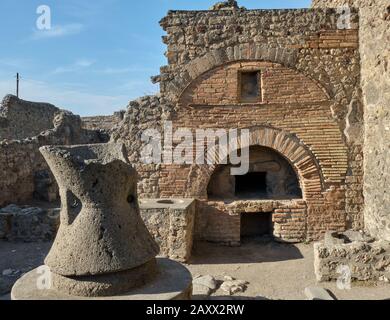 Brick bread oven and a flour mill at a bakery in the Roman ruins of Pompeii Stock Photo