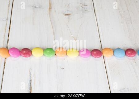 Lot of whole sweet colourful candy line on white wood Stock Photo