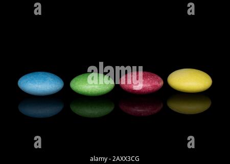 Group of four whole sweet colourful candy isolated on black glass Stock Photo