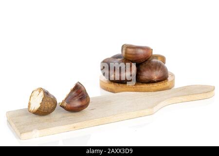 Group of five whole two halves of edible brown chestnuts on coaster and cutting board isolated on white background Stock Photo