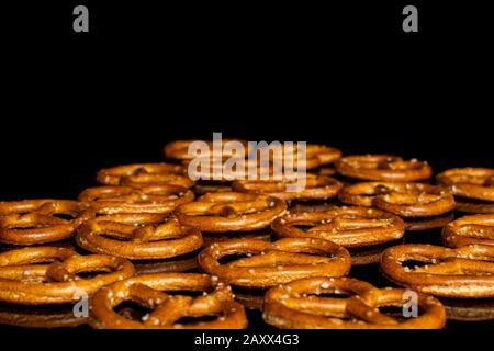 Lot of whole salty brown pretzel isolated on black glass Stock Photo