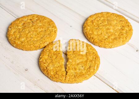Group of two whole two halves of sweet golden oat cookie on white wood Stock Photo