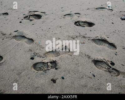 Human shoes steps footprints on wild sandy sea beach,texture wallpaper Stock Photo