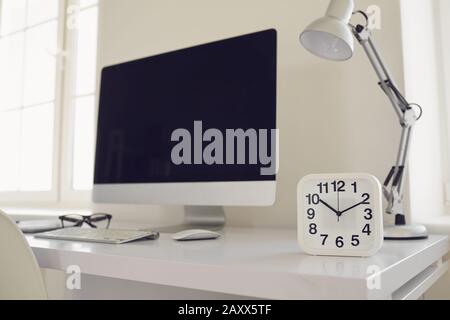 White modern workplace with windows computer alarm clock on the table Stock Photo