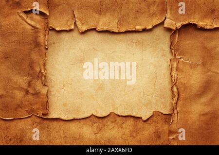 Four old crumpled torn ancient sheets of paper on another vintage sheet of paper form a rectangular frame with copy space. Stock Photo