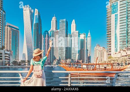 Cheerful asian traveler girl walking on a promenade in Dubai Marina district. Travel destinations and tourist lifestyle in UAE Stock Photo