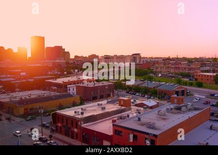 View of Bricktown Oklahoma City over rooftops with the sun glowing brightly as it goes down Stock Photo