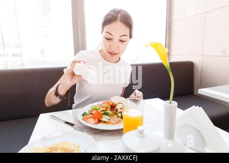 Asian woman in casual clothes having continental breakfast in hotel restaurant Stock Photo