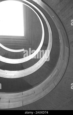 Architectural structure in grey concrete. Multi-level structure with a circular design illuminated by light from above. Stock Photo
