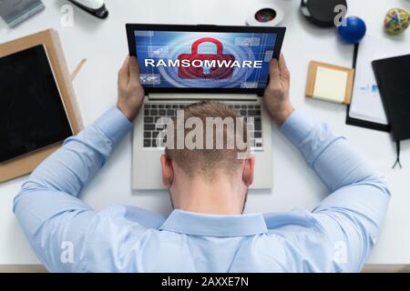 High Angle View Of Sad Man With Laptop Infected By Malware Stock Photo
