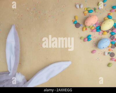 Cute creative composition with multi colored easter eggs, colorful sweets, and bunny ears. Easter and Springtime concept Stock Photo