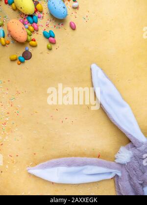 Cute creative composition with multi colored easter eggs, colorful sweets, and bunny ears. Easter and Springtime concept Stock Photo