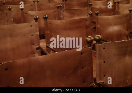 Leather chairs. Rows of vintage brown leather seats inside a conference room with metal knobs. Stock Photo