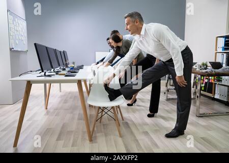 Group Of Happy Young Businesspeople Doing Stretching Exercise In Office Stock Photo