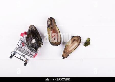 Rotten avocado in a mini food cart with two half od moldy avocado. Stop wasting food concept, eating stale food. Stock Photo