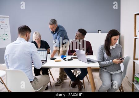 Distracted Businesswoman Using Mobile Phone In Meeting Stock Photo