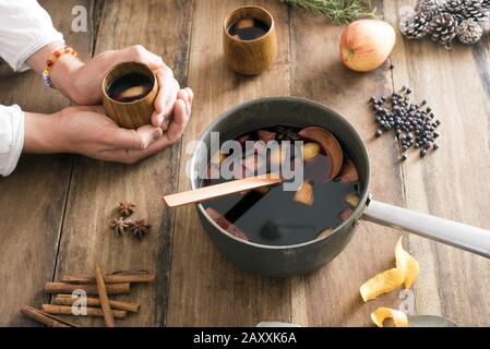 https://l450v.alamy.com/450v/2axxk6a/delicious-spicy-hot-mulled-wine-as-a-winter-warmer-with-a-person-cradling-a-cup-in-their-hands-alongside-a-pot-filled-with-a-freshly-made-brew-with-sp-2axxk6a.jpg