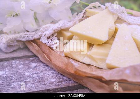 Pieces of cocoa butter with lace and white flowers. White chocolate on brown color paper. Stock Photo