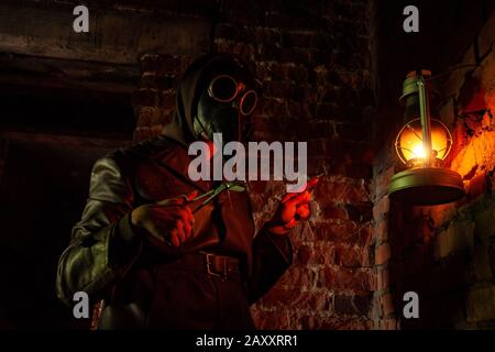 Terrible plague doctor on red brick background. Masked maniac with scalpel and scissors. Halloween and horror Stock Photo