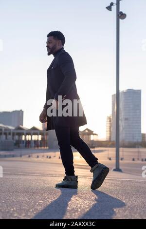 Rear view of black young bearded man walking outdoors while looking away Stock Photo