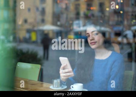 Young businesswoman in a cafe- seen through window Stock Photo