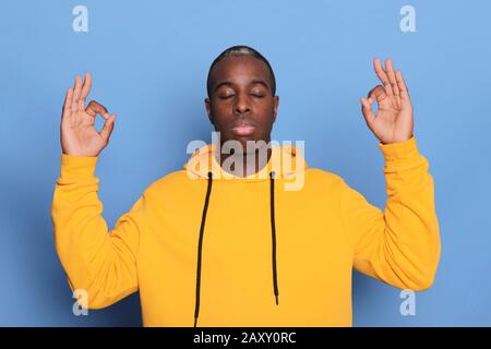 One young african black man relaxes after hard working day, he is performing yoga. Stock Photo
