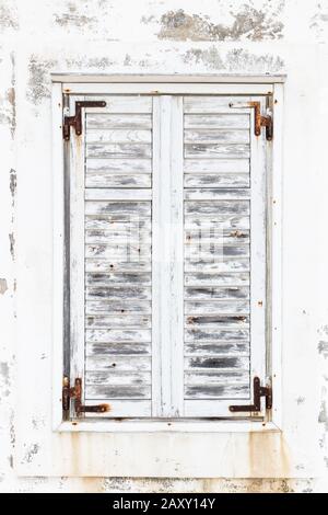 White weathered rusted wooden window shutters.