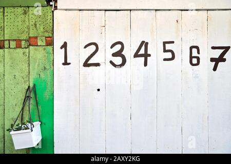 The entrance of a shop is closed with white and green painted wooden panels, which are marked with big numbers, often seen in the Philippines, Asia Stock Photo