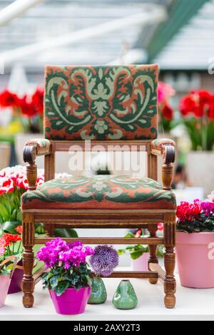 Wooden arm chair with beautiful fabric upholstery and flowers in the background Stock Photo