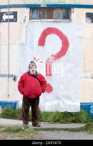 Man standing next to question mark painted on a building in Puerto Natalas, Chile. Stock Photo