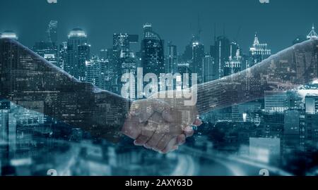 Close up of business handshake for successful of investment deal and city night background, teamwork and partnership concept. Stock Photo