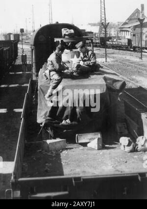 Two American GIs play cards atop a transport train during World War II. Stock Photo