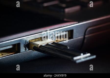 Flash drive in USB port of computer notebook in darkness. Concept of technological advances in computer data recording systems. Stock Photo