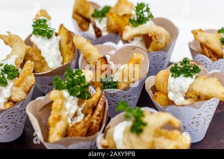 Fish and chips served in paper cones for individual serving. Decorated with parsley. Stock Photo