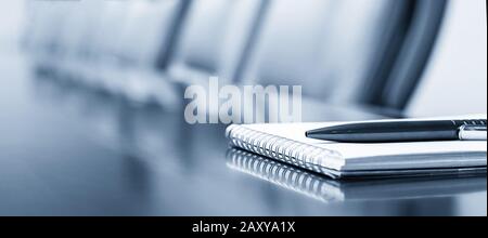 Closeup of notepad kept on table in empty conference room Stock Photo