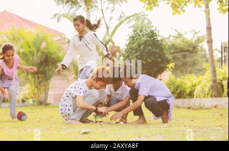 Children playing Lagori, dikori or lagoori outdoor traditional game, where two teams try to hit a pile of stones with ball - concept of kids enjoying Stock Photo