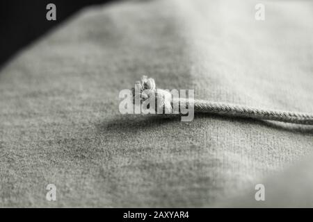 Knotted drawstring on a Light Grey woven cotton fabric textile texture close up macro detailed Stock Photo