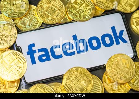 Bangkok, Thailand - July 2, 2019: Phone with Facebook logo on screen is placed with golden coins. Facebook reported to utilize new cryptocurrency call Stock Photo