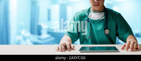 Surgeon doctor sitting at table with tablet computer in hospital office. Medical healthcare staff and doctor service. Stock Photo