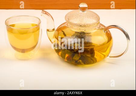 Flower tea brewed in a glass teapot and a glass of tea on a white background. Close up Stock Photo