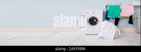 Empty Washing Machine With Pile Of Dirty Cloth In The Basket At Laundry Room Stock Photo