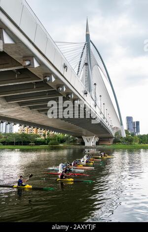 Kayakers paddling as they race under the Seri Wawasan Bridge on Putrajaya Lake by the Putra Mosque. Stock Photo