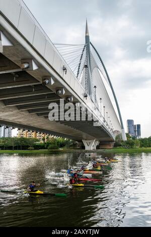 Kayakers paddling as they race under the Seri Wawasan Bridge on Putrajaya Lake by the Putra Mosque. Stock Photo