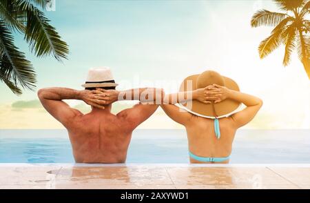 Couple In Infinite Swimming Pool With Palm Trees In Background Stock Photo