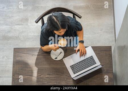 Top view photo of woman using computer and having coffee Stock Photo