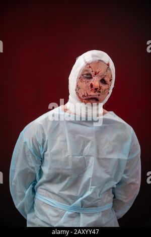 Crazy zombie horror make up. Person in blue madical shirt and bandaged head. Scars, deep scratches realistic art make-up. head is re-banded bandage Stock Photo