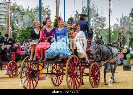 Women wearing traditional Spanish dresses riding on carriage, Jerez Horse Fair (Feria de Caballo) , Jerez de la Frontera, Andalusia, Spain Stock Photo