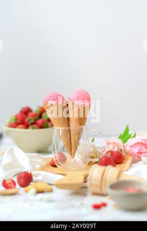 Cropped shot of summer dessert with strawberry flavour ice-cream cones and topping on marble desk Stock Photo